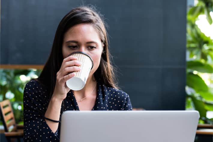 Woman browsing on laptop and sipping coffee